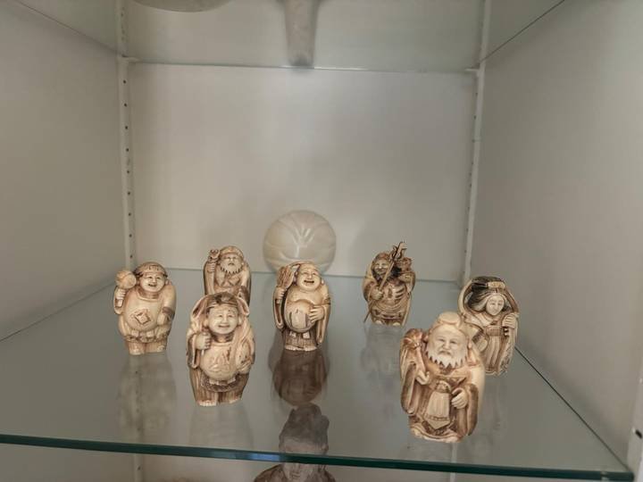 Petites statuettes sculptées alignées sur une étagère de vitrine