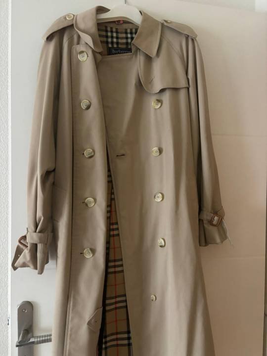 Trench-coat beige à doublure à carreaux sur un cintre